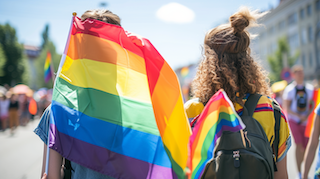 Two people joining the pride parade holding up pride flags 